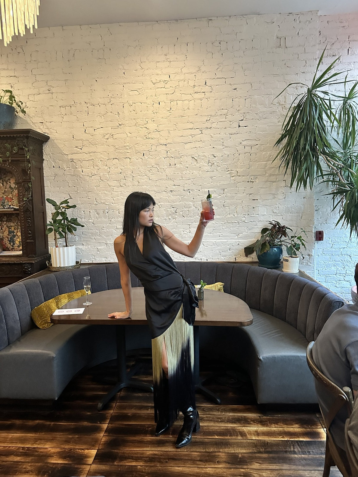 Fringe halter wrap dress, full length in the booth with a cocktail