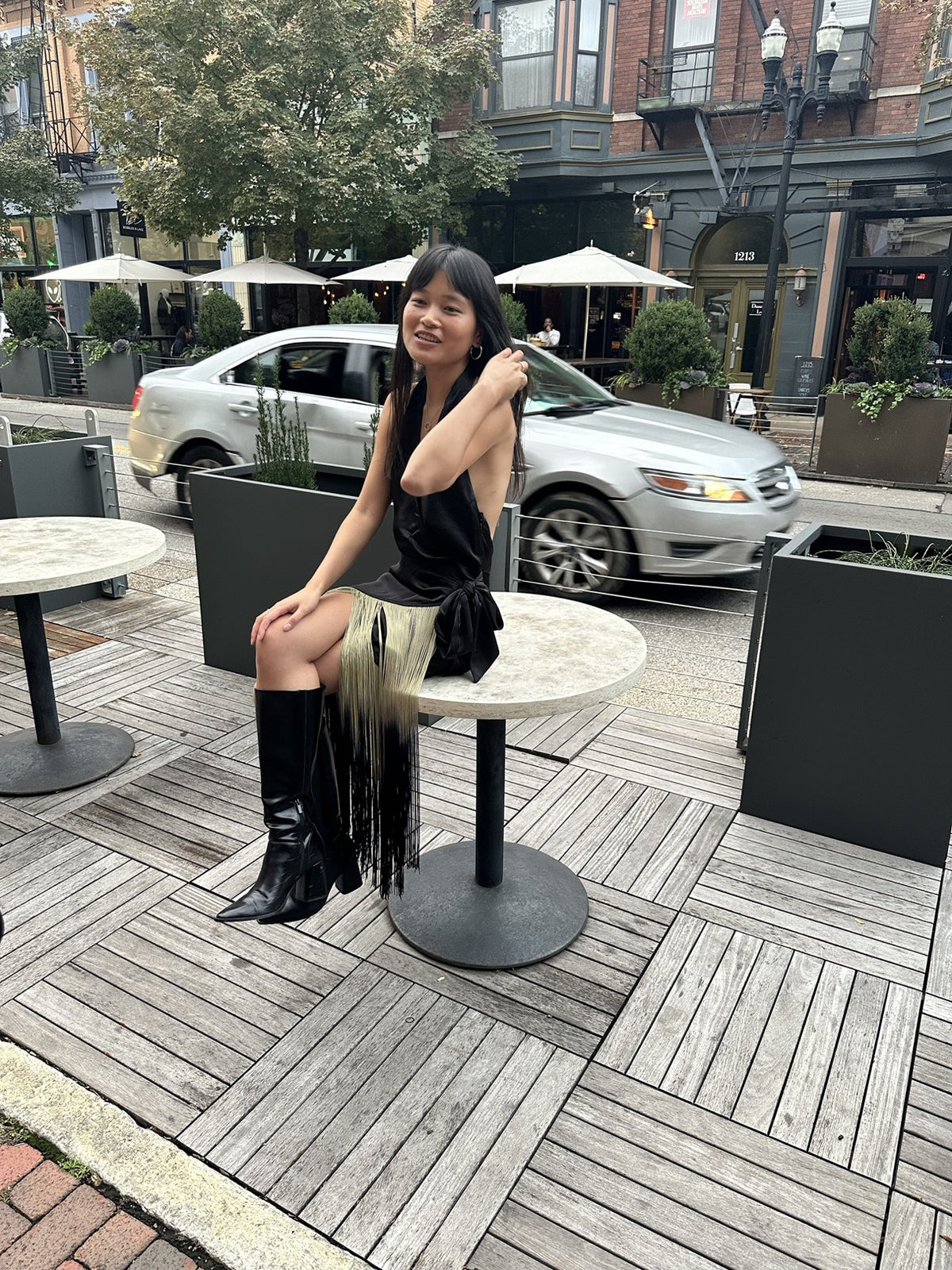 Fringe halter wrap dress with knee boots, seated on the patio